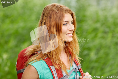 Image of smiling young woman with backpack hiking in woods