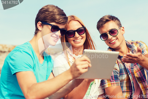 Image of group of smiling friends with tablet pc outdoors