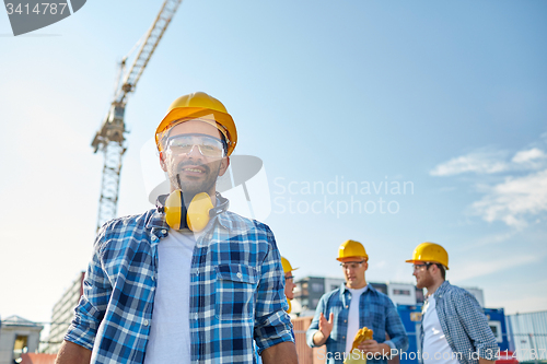 Image of group of smiling builders in hardhats outdoors