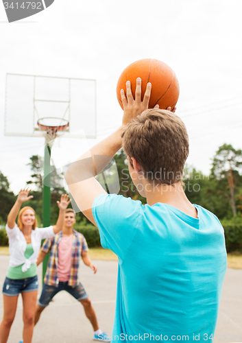 Image of group of happy teenagers playing basketball