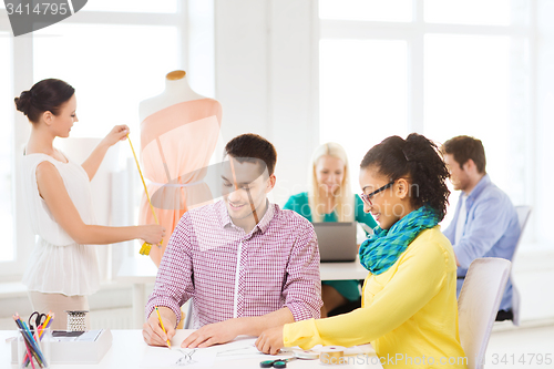 Image of smiling fashion designers working in office