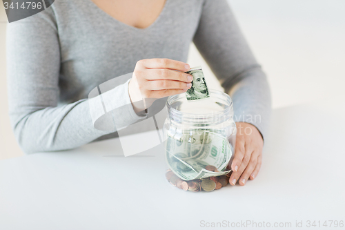Image of close up of woman hands and dollar money in jar