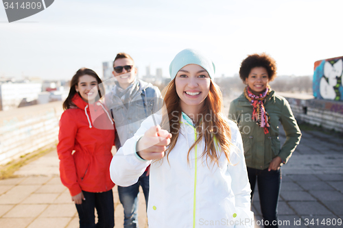 Image of happy friends pointing finger to you on street