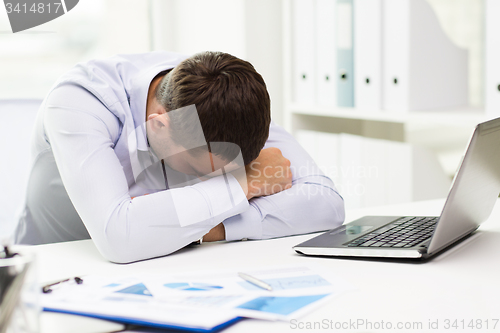 Image of businessman with laptop and papers in office