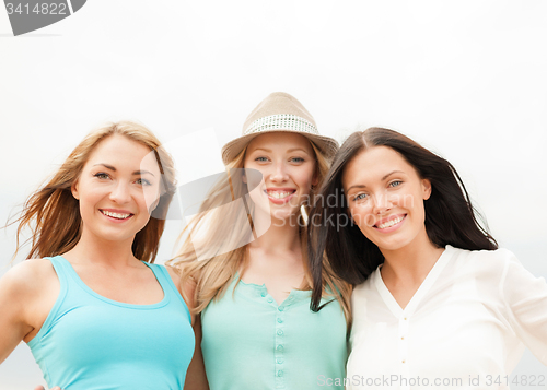 Image of group of smiling girls chilling on the beach