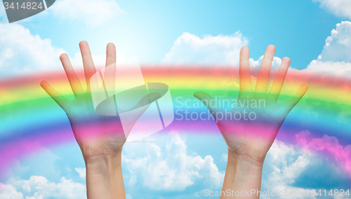 Image of palms of human hands thumbs up over rainbow in sky