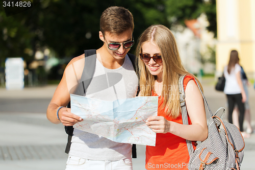 Image of smiling couple with map and backpack in city