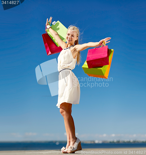Image of smiling woman with shopping bag rising hands