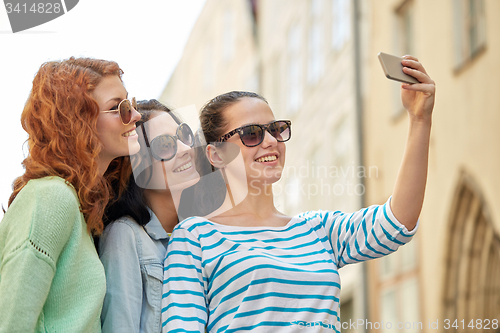 Image of smiling young women taking selfie with smartphone