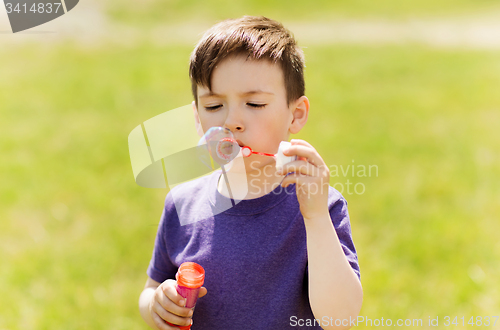 Image of little boy blowing soap bubbles outdoors