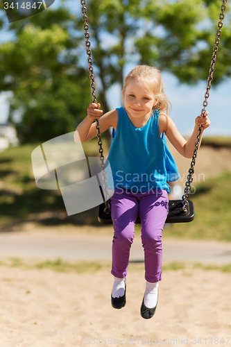 Image of happy little girl swinging on swing at playground