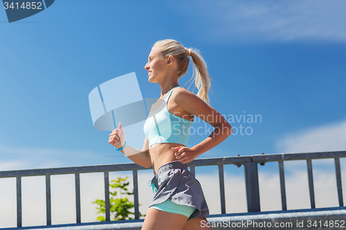 Image of smiling young woman running outdoors