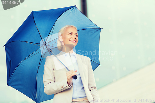 Image of young smiling businesswoman with umbrella outdoors