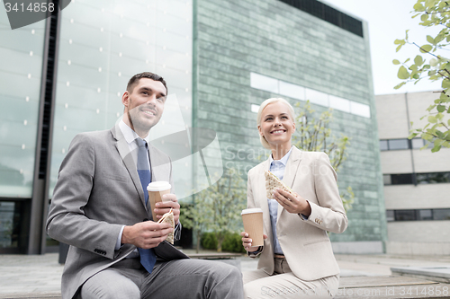 Image of smiling businessmen with paper cups outdoors