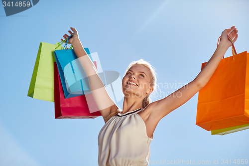 Image of smiling woman with shopping bag rising hands