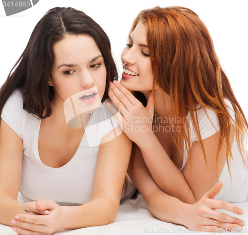 Image of two smiling girls whispering gossip