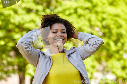 Image of happy african american young woman in summer park