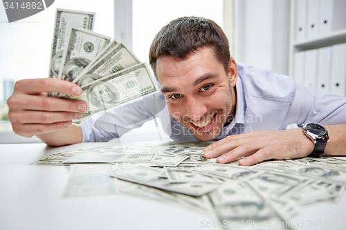 Image of happy businessman with heap of money in office