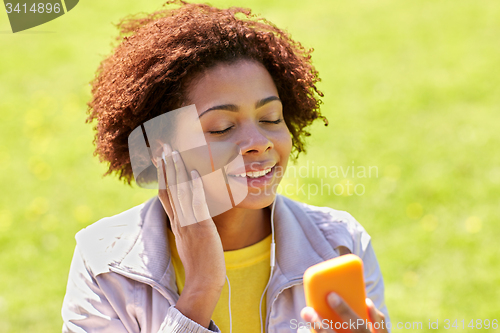 Image of happy african woman with smartphone and earphones