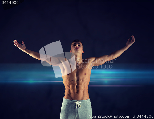 Image of young male bodybuilder with raised hands
