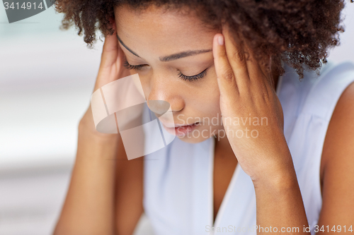 Image of close up of african young woman touching her head