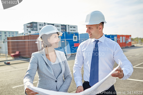 Image of happy architects with blueprint at building