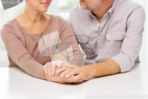 Image of close up of senior couple holding hands at home