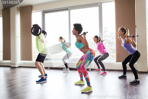 Image of group of people exercising with barbell in gym