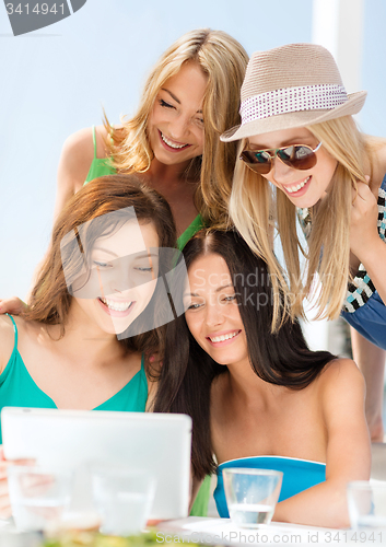 Image of smiling girls looking at tablet pc in cafe