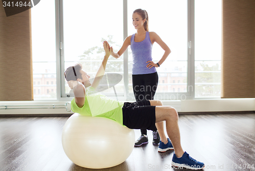 Image of smiling man and woman with exercise ball in gym