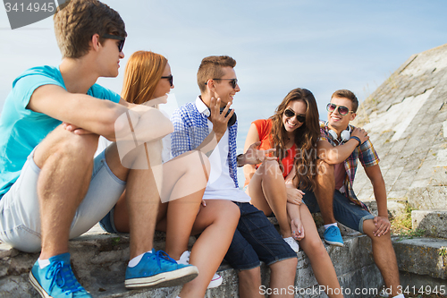 Image of happy teenage friends talking outdoors