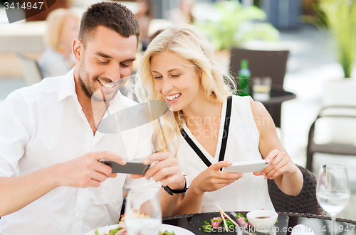 Image of happy couple with smatphone photographing food