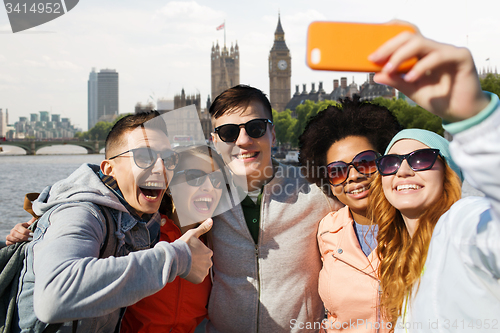 Image of smiling friends taking selfie with smartphone