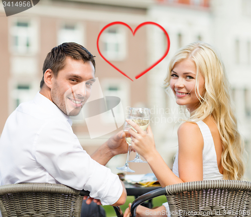 Image of smiling couple drinking wine in cafe