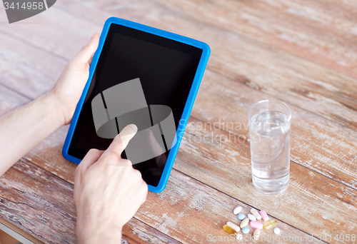 Image of close up of hands with tablet pc, pills and water