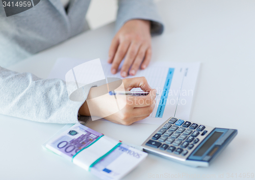 Image of close up of hands counting money with calculator