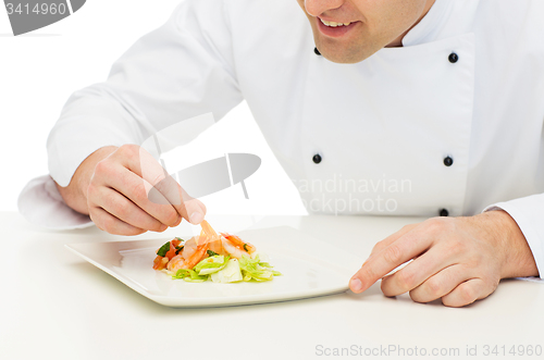 Image of close up of happy male chef cook decorating dish