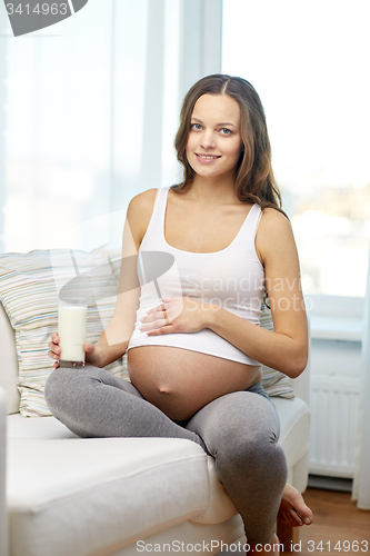 Image of happy pregnant woman drinking milk at home