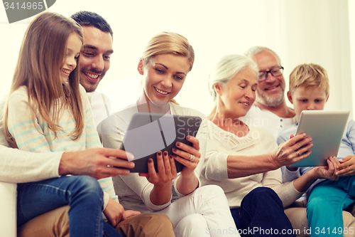 Image of smiling family with tablet pc at home