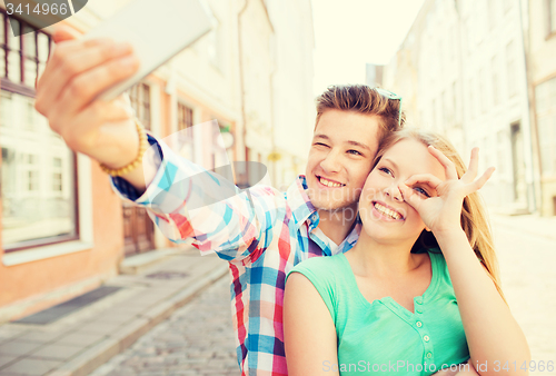 Image of smiling couple with smartphone in city