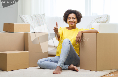 Image of happy african woman with cardboard boxes at home