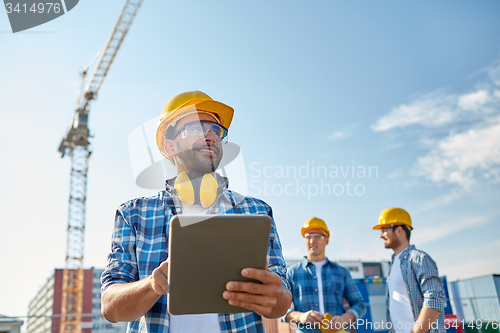 Image of builder in hardhat with tablet pc at construction