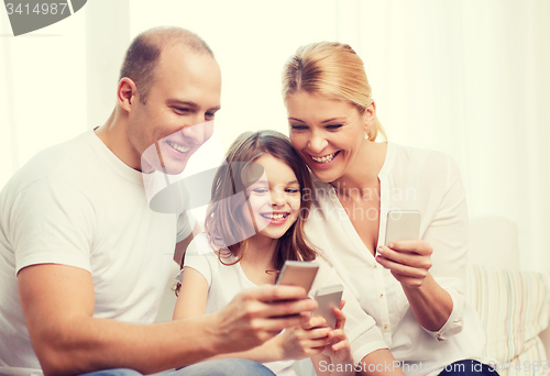 Image of parents and little girl with smartphones at home