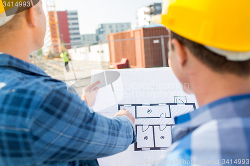 Image of close up of builders with blueprint at building