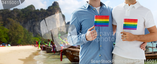 Image of close up of male gay couple with rainbow flags