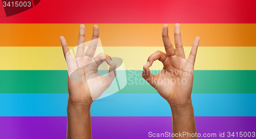 Image of hands showing ok sign over rainbow background