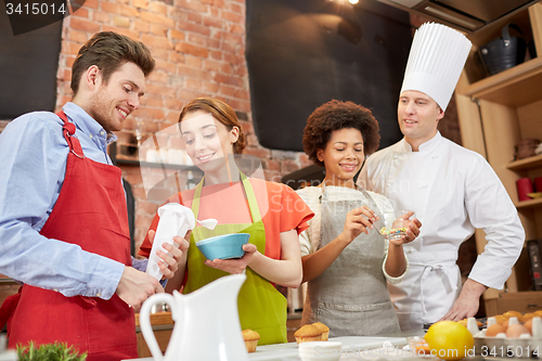 Image of happy friends and chef cook baking in kitchen