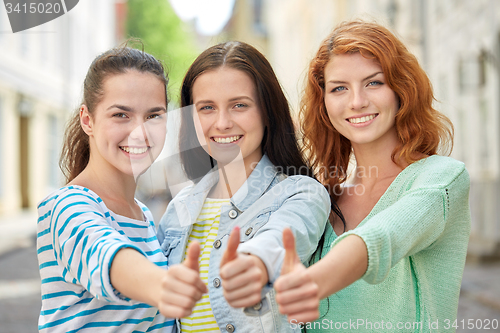 Image of happy young women showing thumbs up on city street