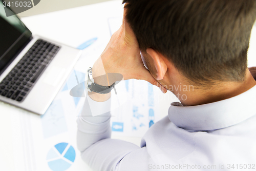 Image of close up of businessman with laptop and papers