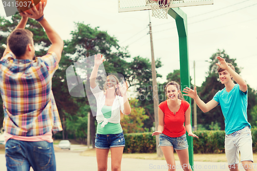 Image of group of smiling teenagers playing basketball